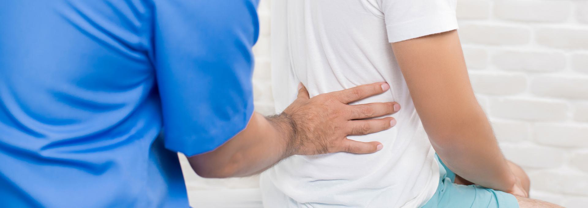 Kraus Weber Lower Back Exam Healthcare professional in blue uniform examining a patient's back.