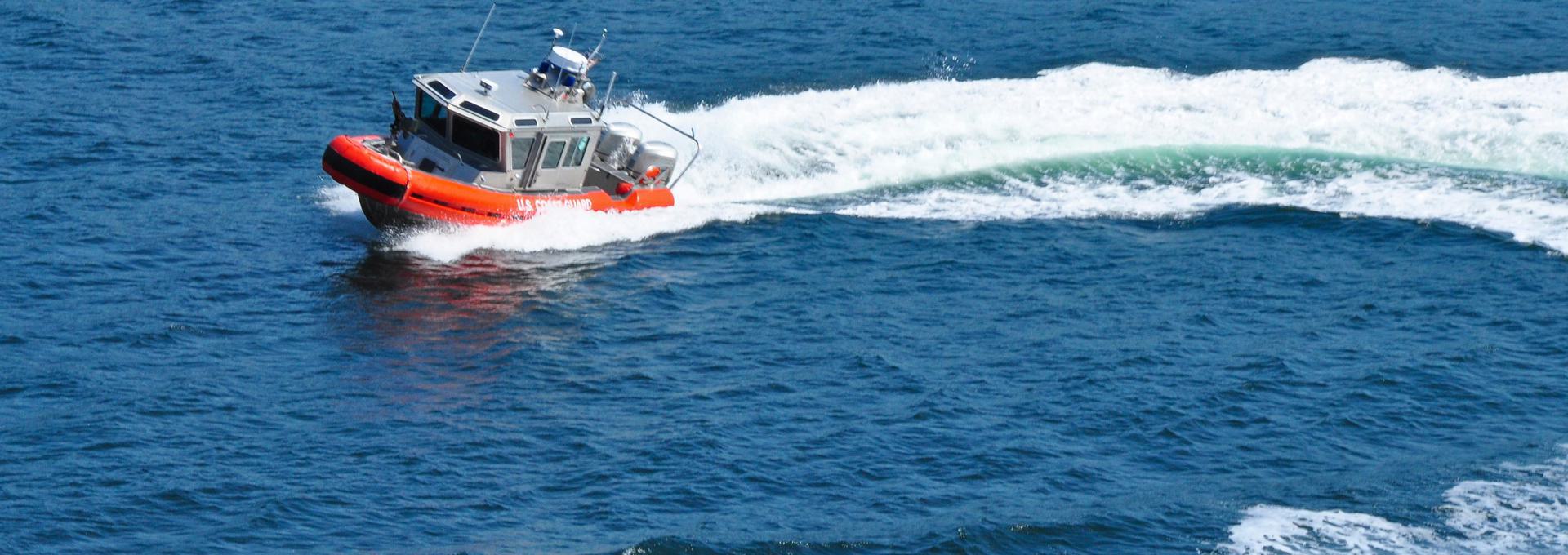 Coast Guard Boat in Action U.S. Coast Guard boat speeding through ocean waters, creating a white wake.