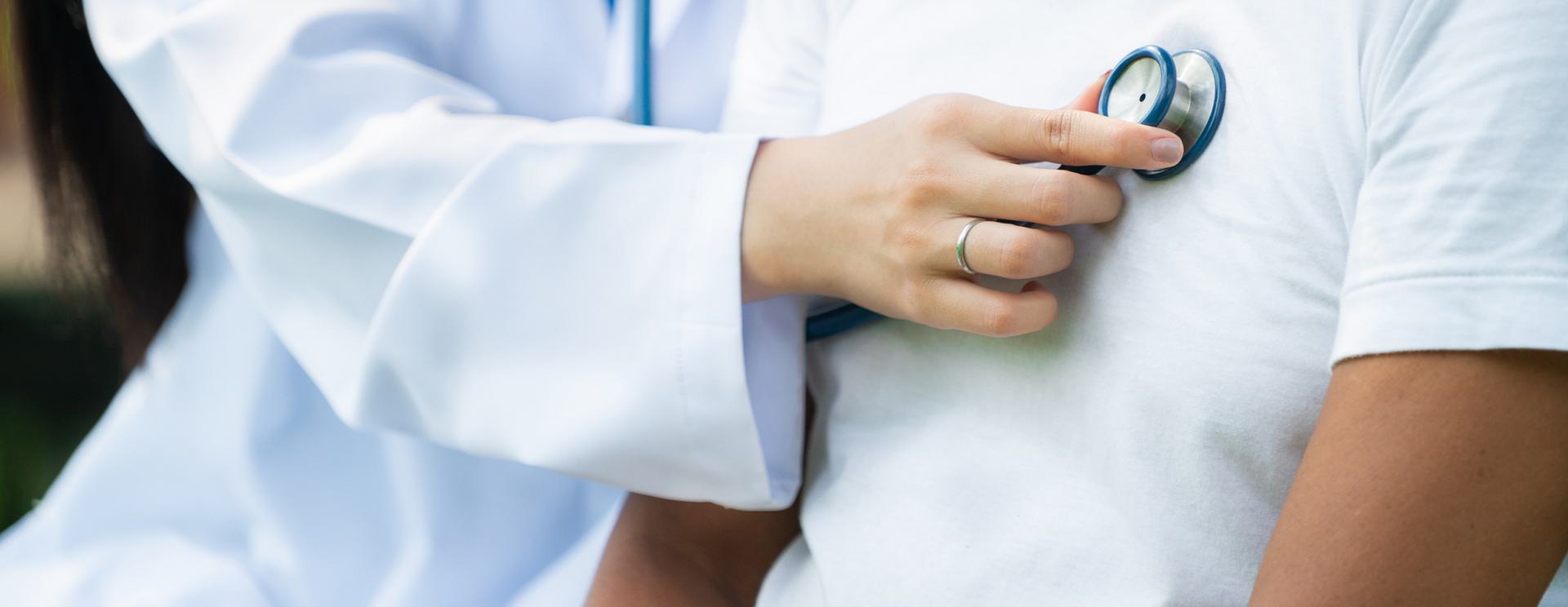Doctor using a stethoscope on a patient's chest during a medical examination.