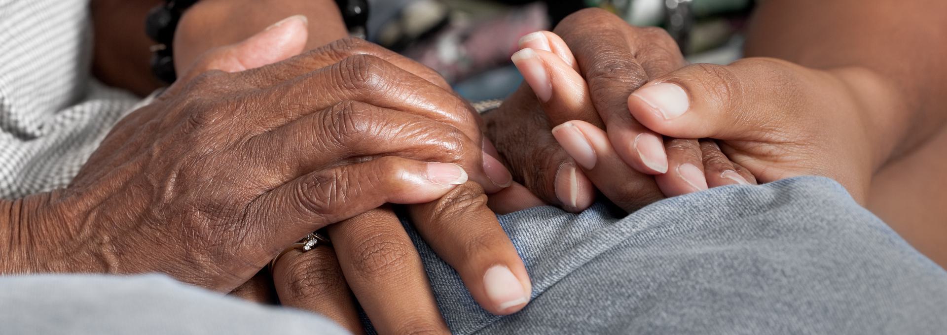 Close-up of two people holding hands, symbolizing a child with their grandparent.