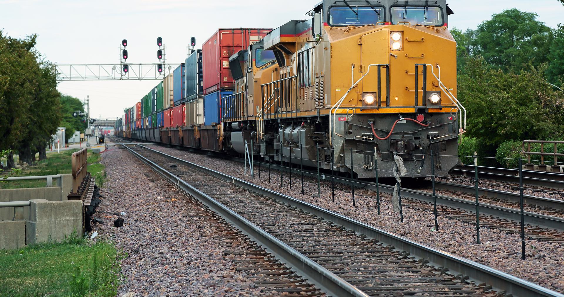 FRA Contractor Drug Testing Program Freight train with yellow locomotive pulling colorful cargo containers on railway tracks.