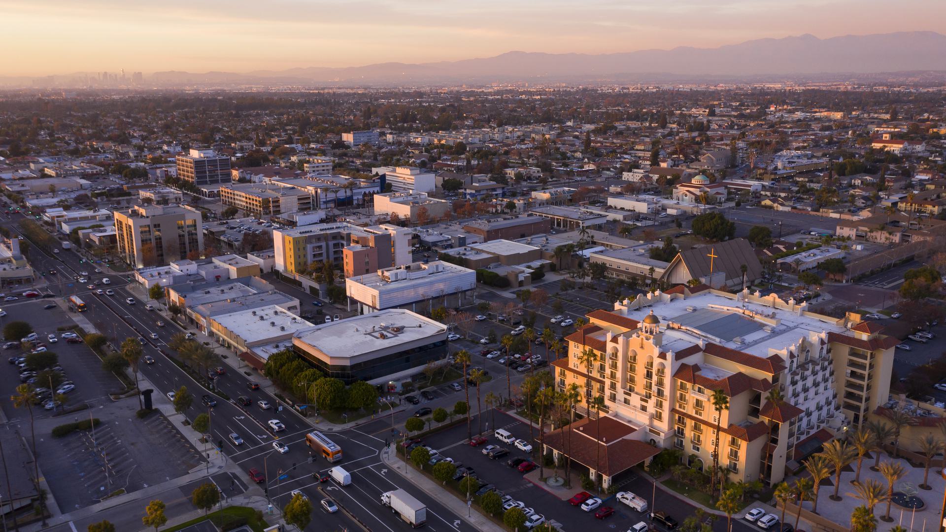Cityscape at Sunset Aerial view of a cityscape at sunset with buildings, roads, and distant mountains.