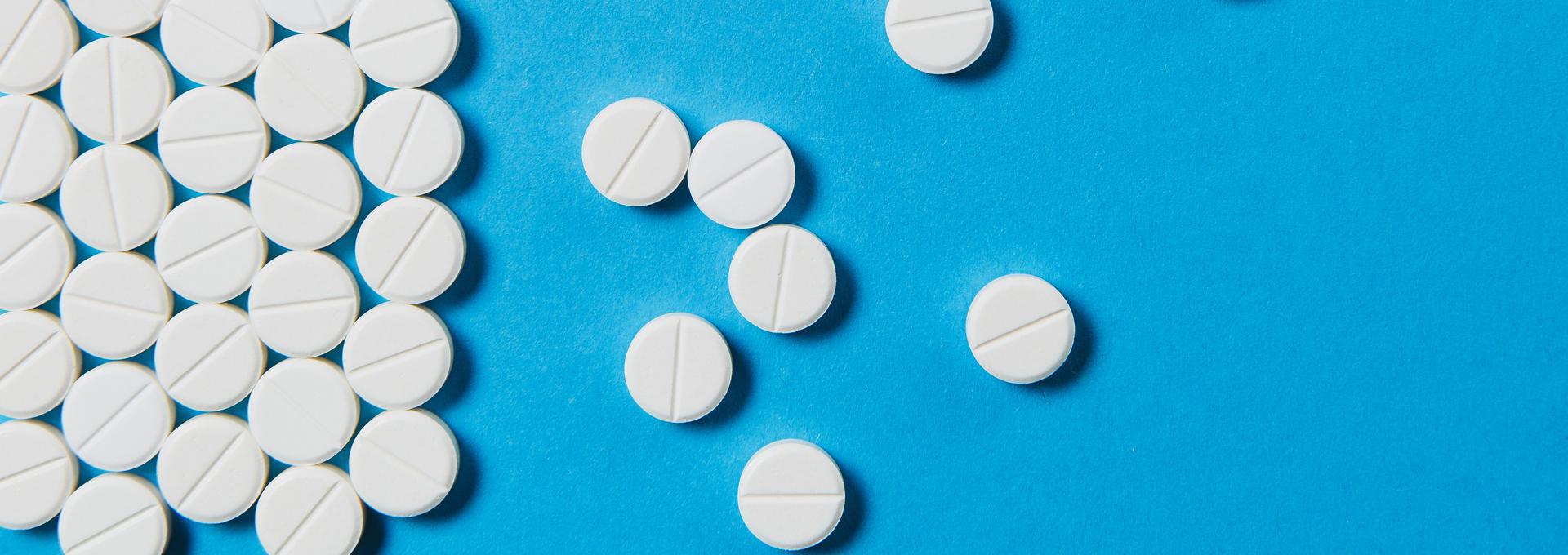 Rohypnol Drug Test White round tablets scattered on a blue background.