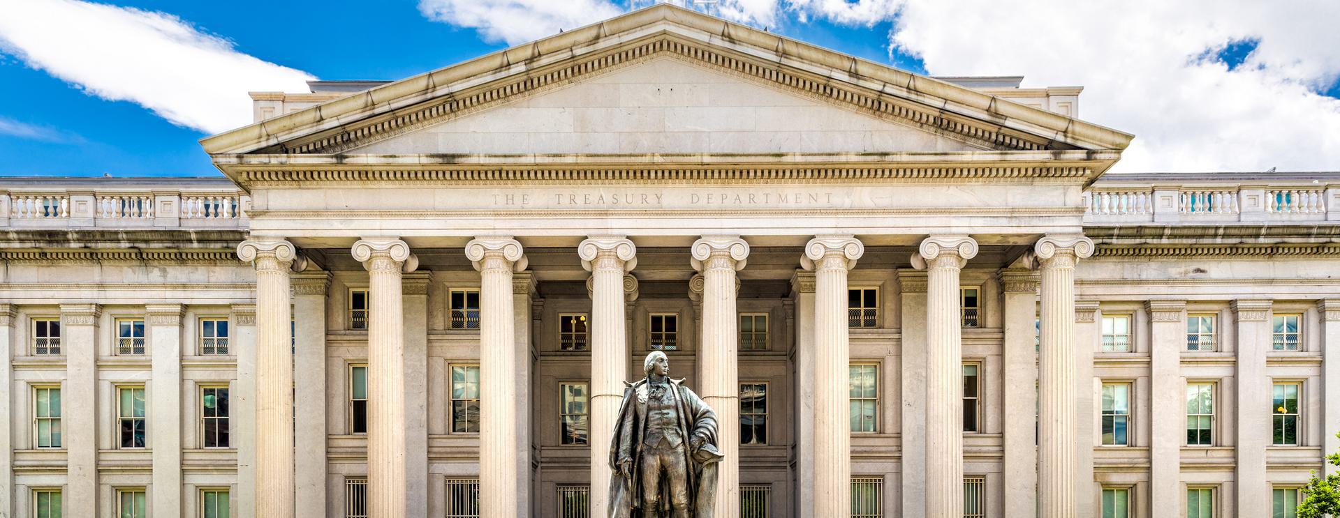 OFAC Sanctions Front view of the U.S. Treasury Department building with a statue in front, featuring neoclassical architecture and columns under a blue sky.
