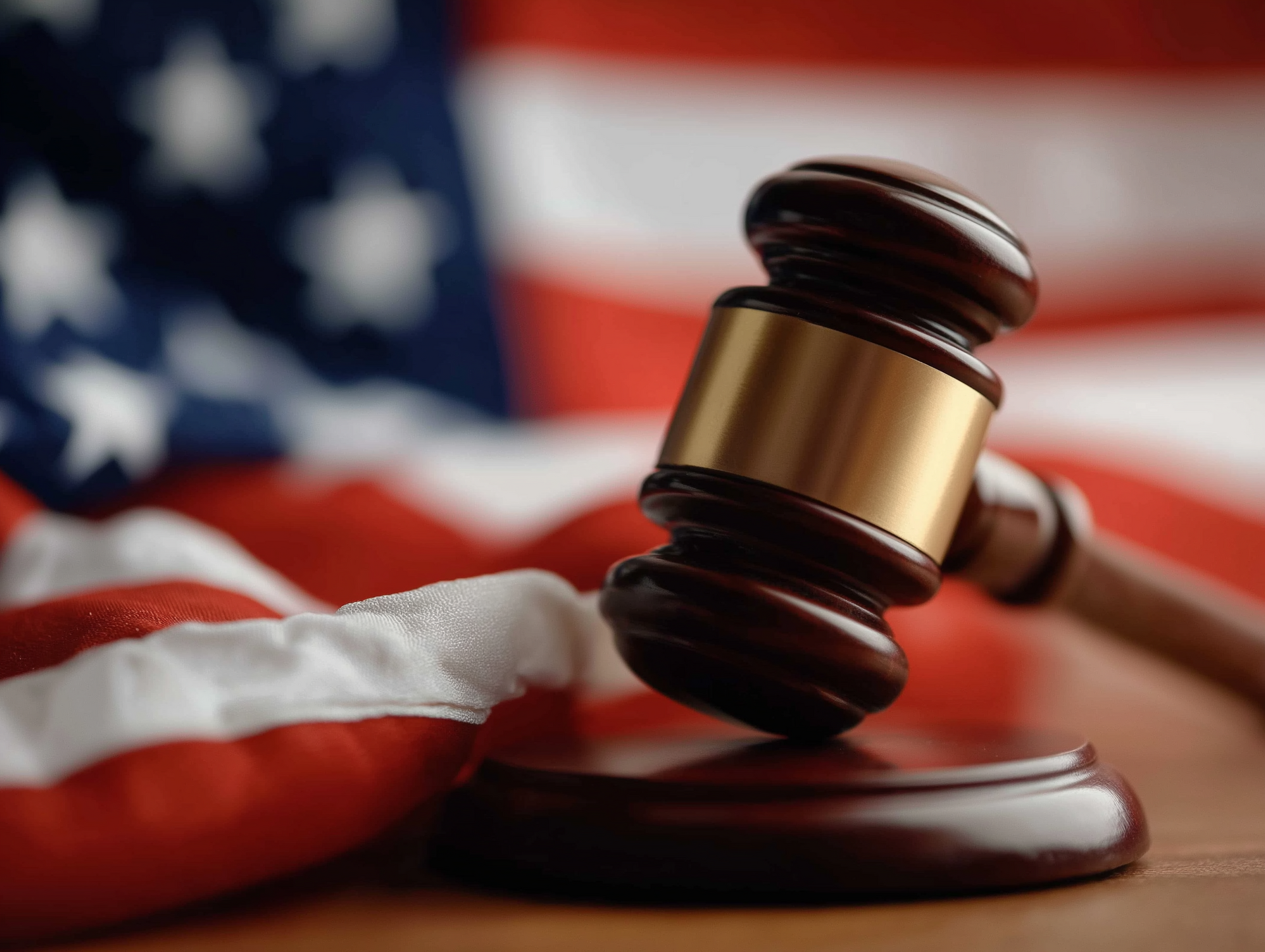 Judge's gavel resting on a block with the American flag in the background, symbolizing justice and law.