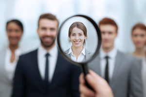 Magnifying glass focusing on a smiling woman in a group of business professionals.