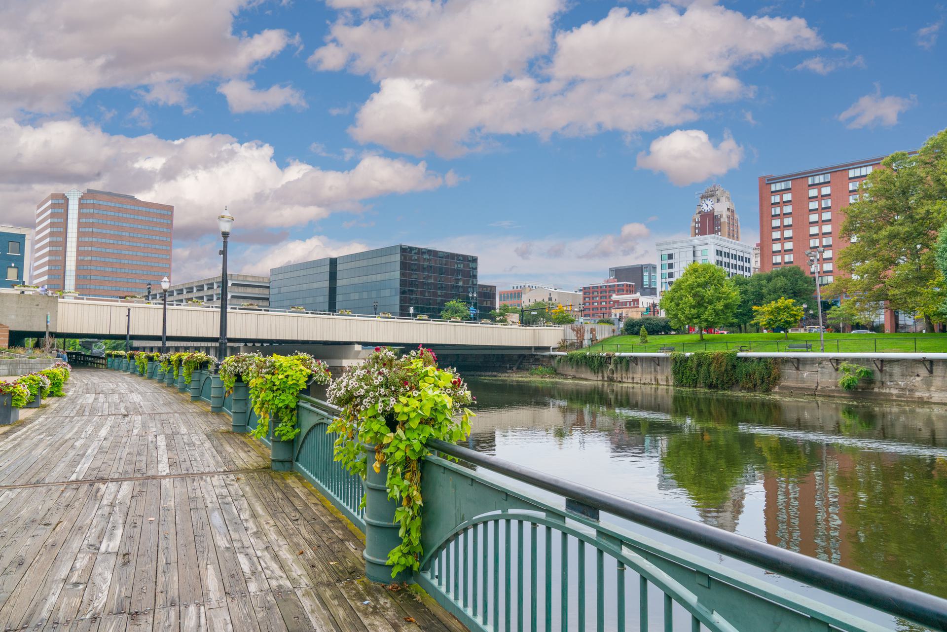 Riverside Walkway and Cityscape Scenic view of a riverside walkway with planters, modern buildings in the background, and a clear blue sky.