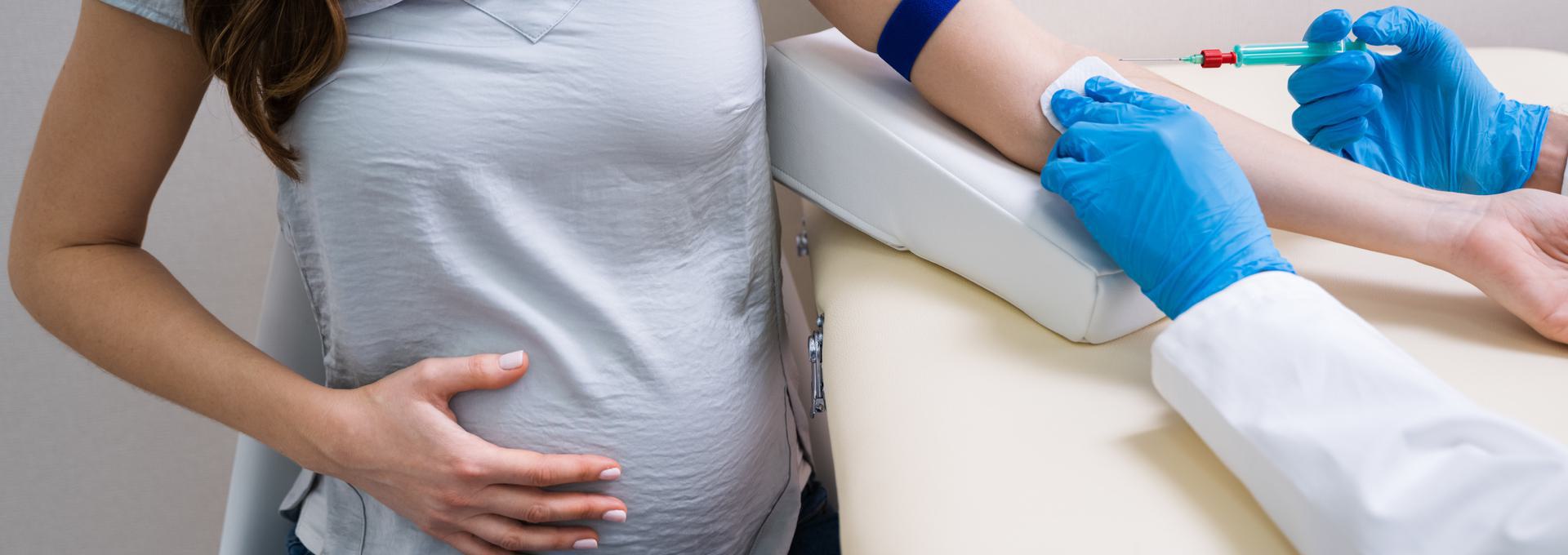 Prenatal Paternity Test Pregnant woman having blood drawn by a healthcare professional wearing blue gloves.
