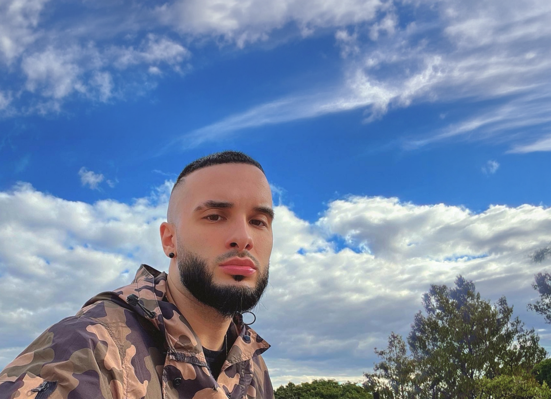 Louis in camouflage jacket with cloudy sky background